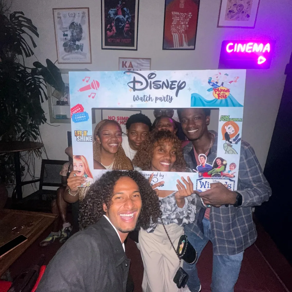 Guests crowding into the Disney Watch Party photo frame beside the neon cinema sign