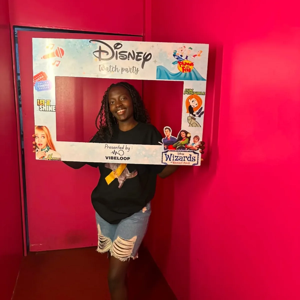 Guest holding the Disney Watch Party photo frame in the pink corridor
