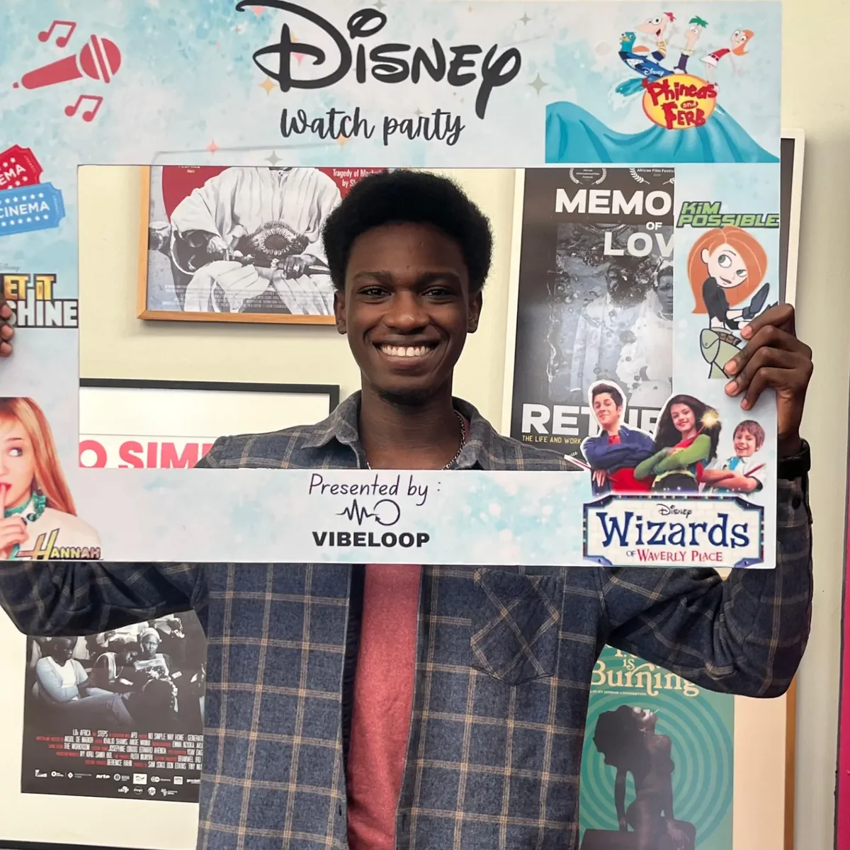 Guest smiling through the Disney Watch Party photo frame among film posters