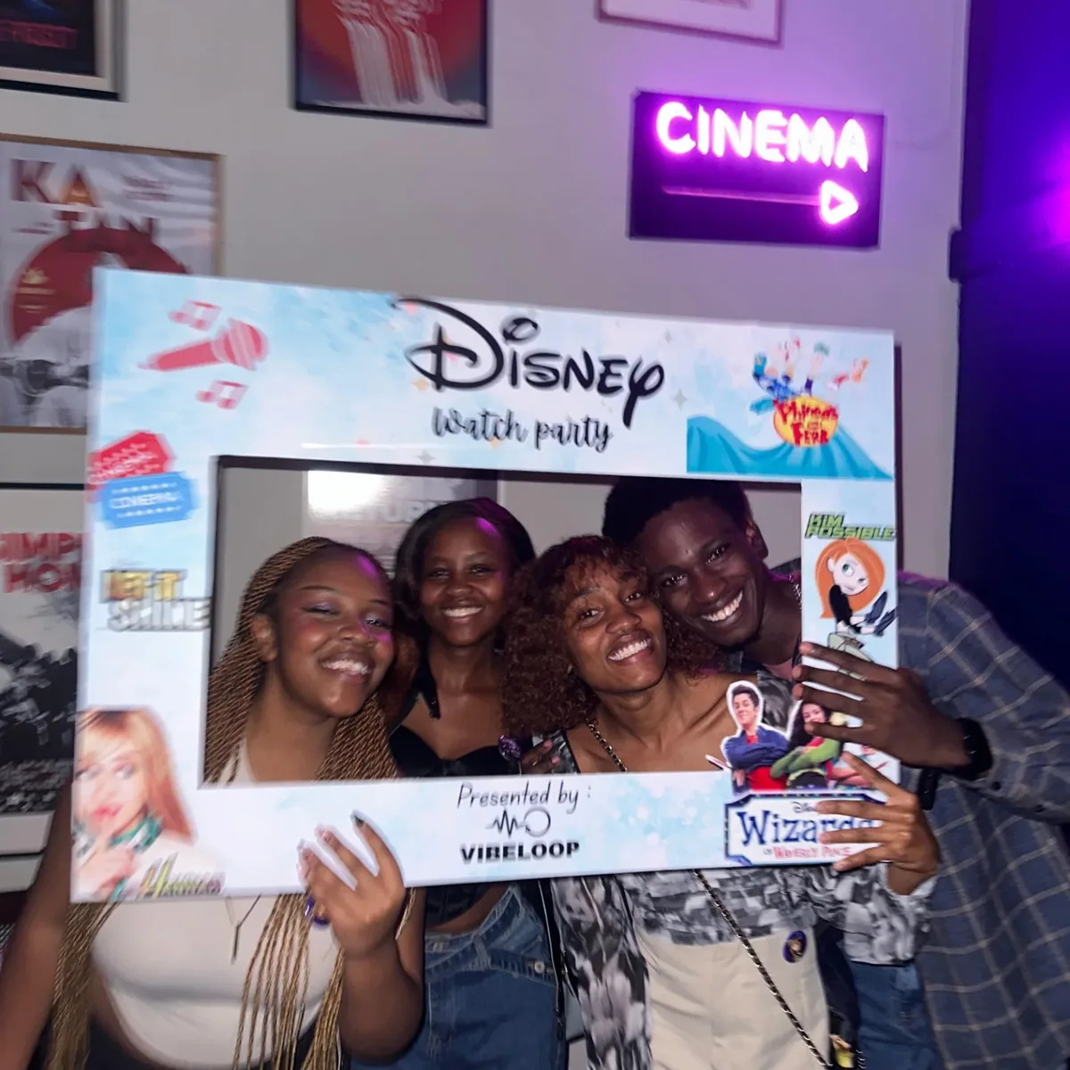 Friends laughing together under the neon cinema sign